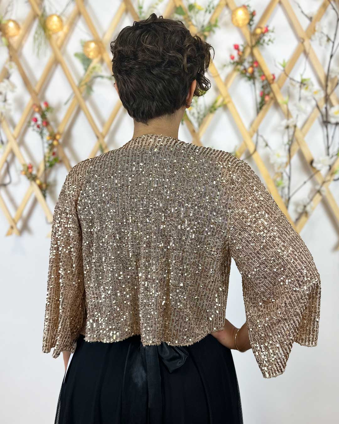 Trasero de la torera dorada donde se aprecia el brillo que las lentejuelas ofrecen. es un modelo super bonito para combinar con tu look de fiesta o vestido de invitada de boda.