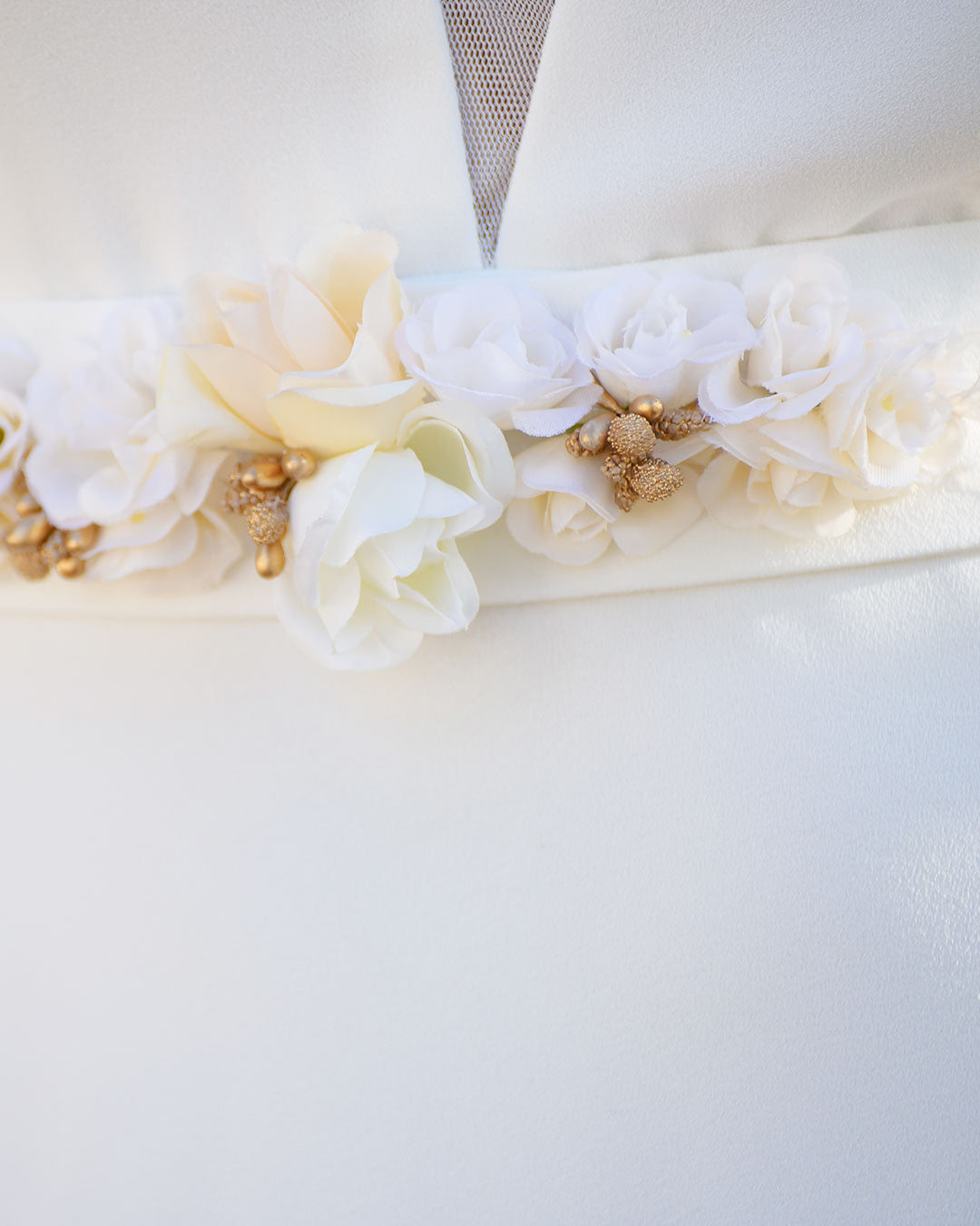 Detalle de cinturón con aplique de flores blancas y doradas.
