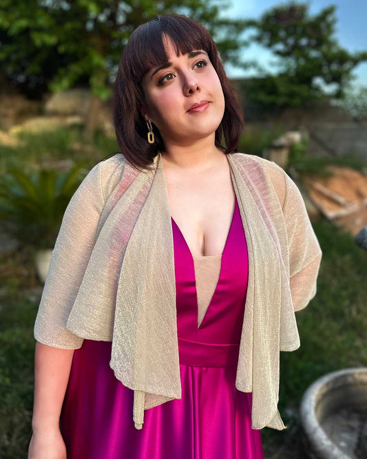 Chica lleva puesto bolero plateado que tapa sus brazos y estiliza su figura. Perfecto para fiestas e invitadas de boda.