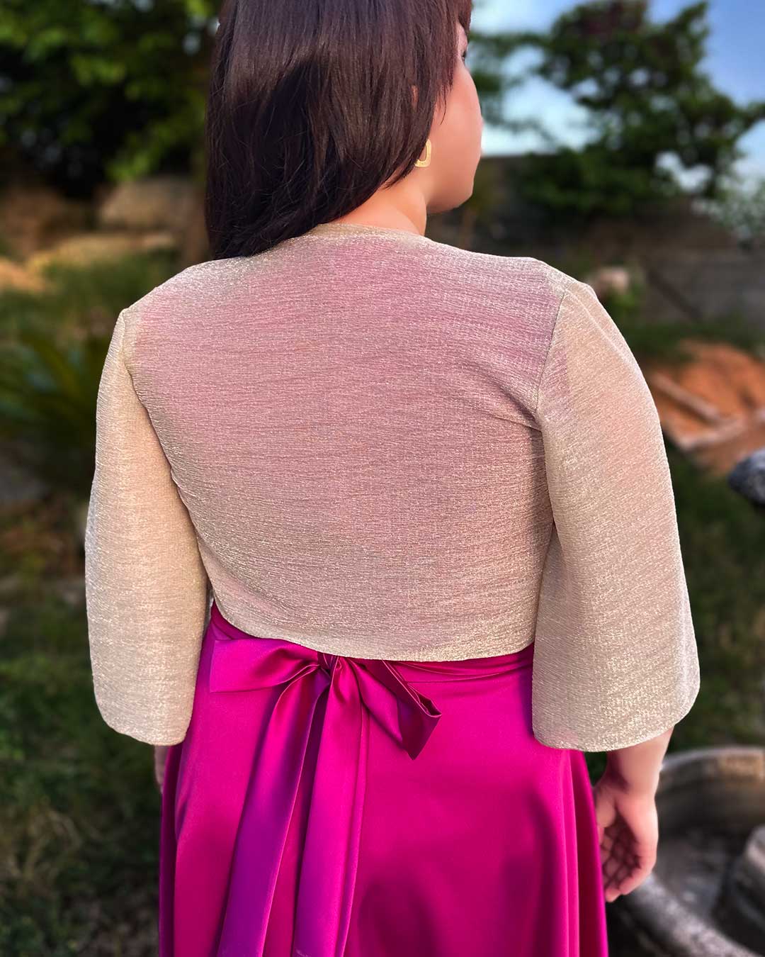 Chica muestra la parte trasera de un bolero dorado transparente, muy elegante y agradable.
