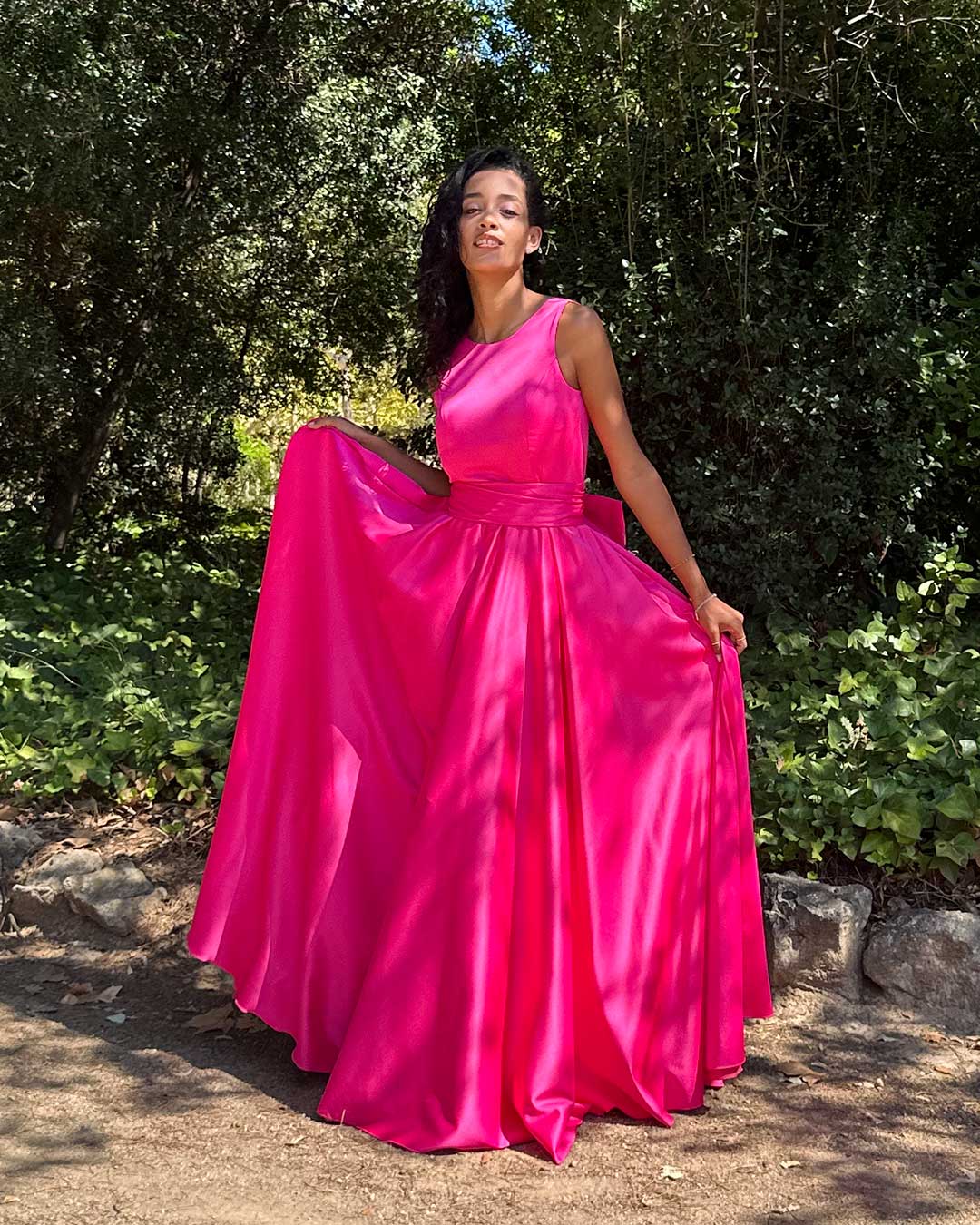 Vestido largo color fucsia de falda acampanada estilo clásico princesa. El escote es redondo y los tirante son anchos.