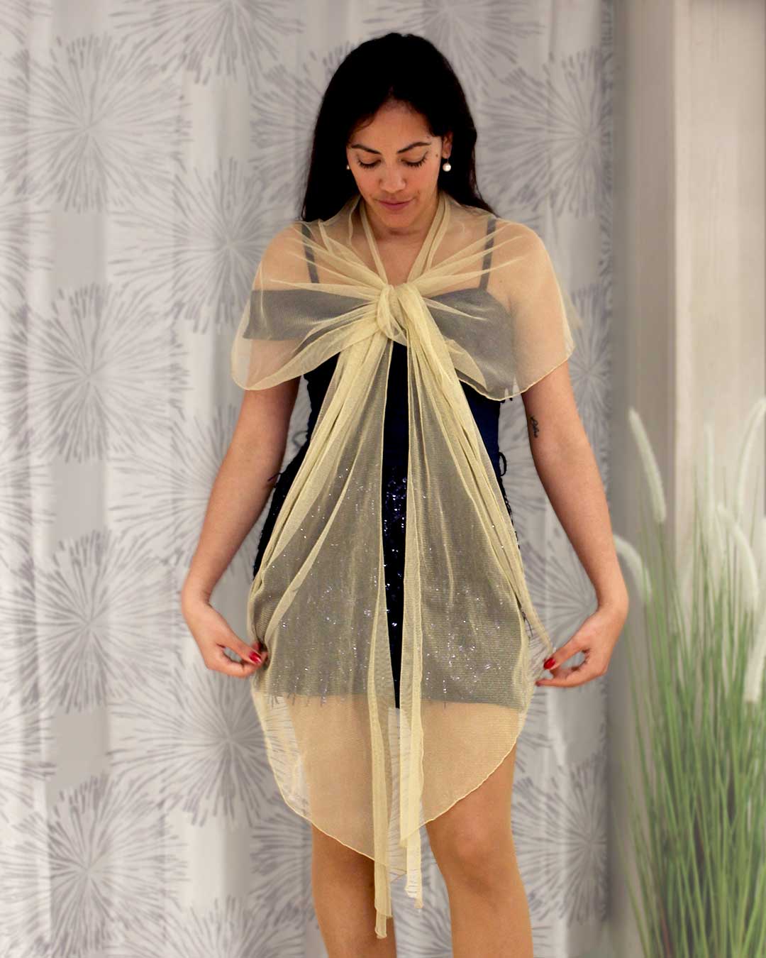 Chal dorado con brillo de tela de gasa puesto sobre los hombros de la modelo con un lazo en el pecho, perfecto para combinar con tu vestido de invitada de boda.