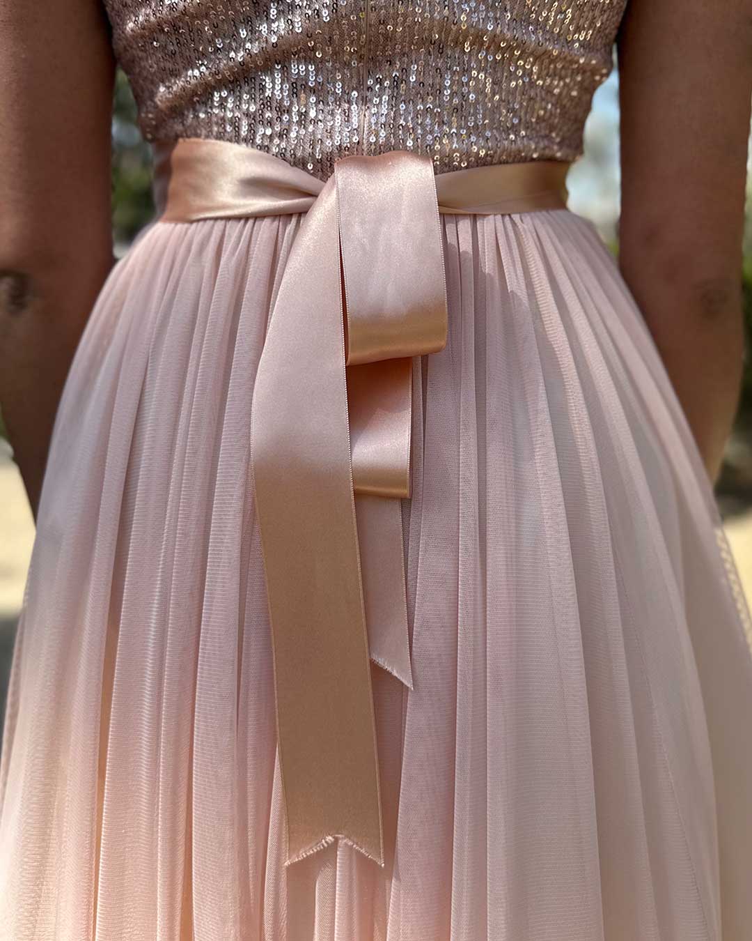 Detalle del cinturón del vestido rosado en tela de raso.