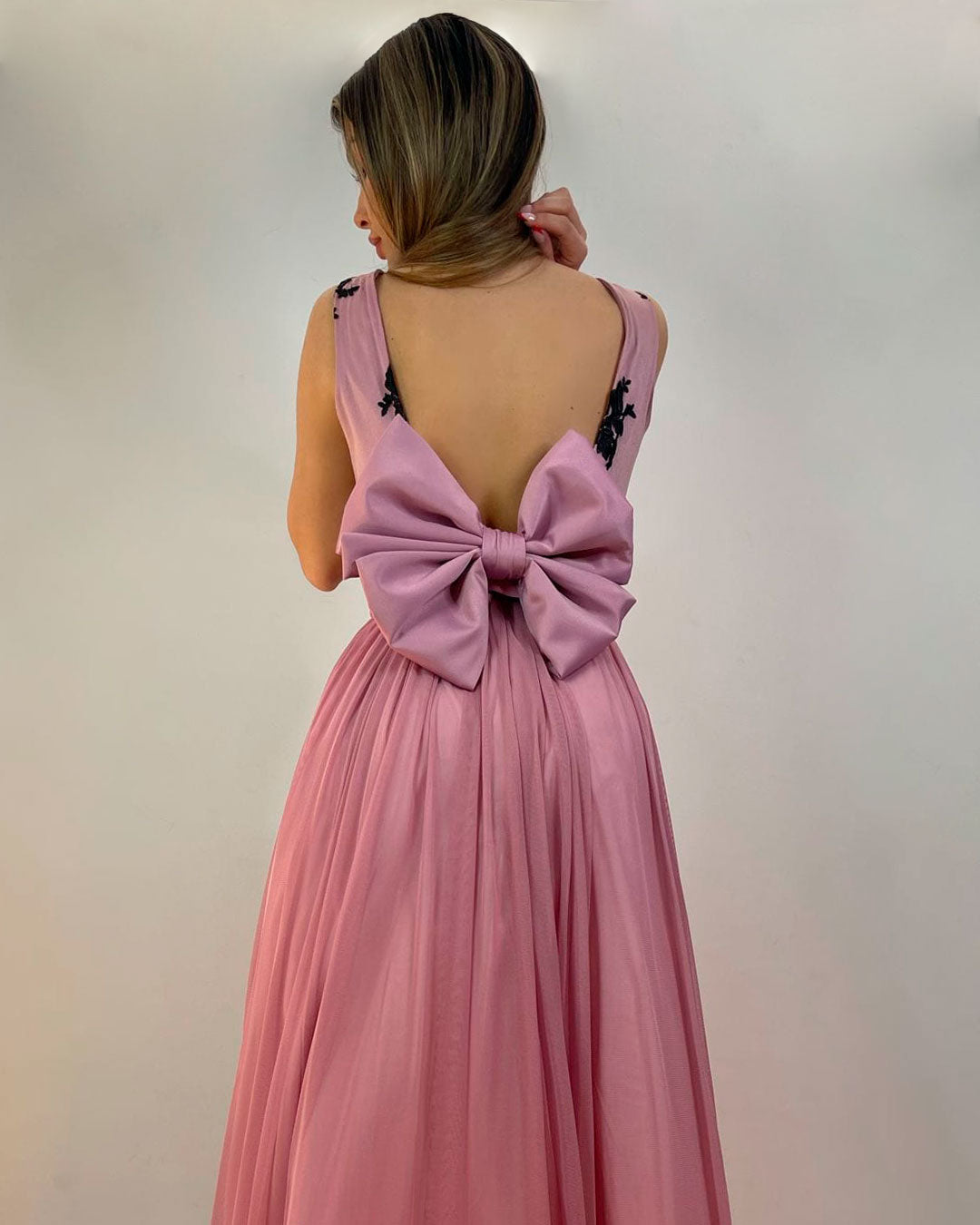 Vestido rosa chicle largo, con falda de gasa, espalda abierta y lazo grande.