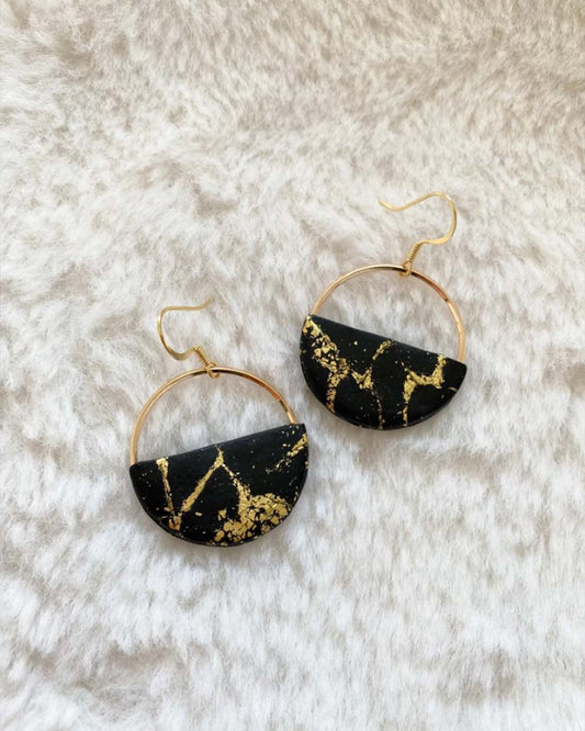 Pendientes dorados con aro y detalle negro con formas de marmol, elegantes y perfecto para invitadas de boda.